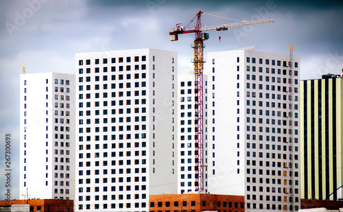 Silhouettes of tower cranes against the evening sky. House under construction. Industrial skyline