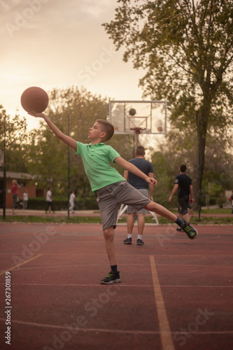 one young boy, holding basketball ball in his hand like a statue.