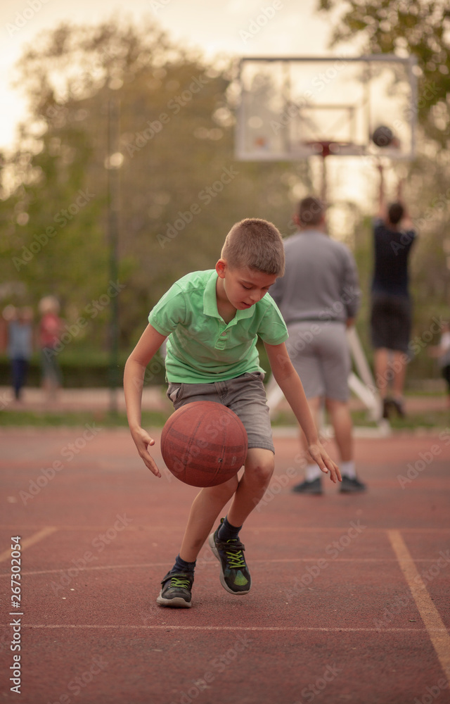 One boy, exercising dribbling ball between his legs.
