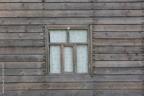 Fragment of one of walls of old village building with window.