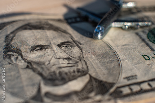 An airplane standing on five dollars. The concept of spending on aviation. The concept of aviation costs. Aviation supervision concept.