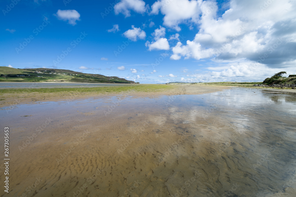 Dunfanaghy Bay at low tide in Donegal, Ireland. White sand and blue sky with clouds at Dunfanaghy beach, a typical irish beach on the northern coast Dunfanaghy Bay at low tide in Donegal, Ireland. White sand and blue sky with clouds at Dunfanaghy beach, a typical irish beach on the northern coast