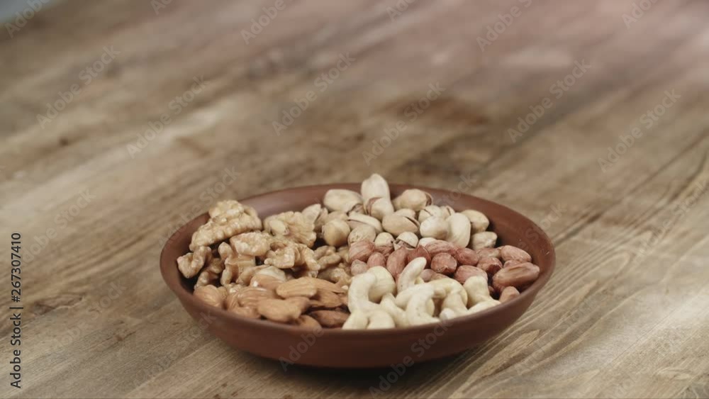 Woman Picks Up a single Cashew, To Eat, From Her Bowl. took a nut on the left side Woman Picks Up a single Cashew, To Eat, From Her Bowl. took a nut on the left side