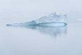 Sculptural iceberg shrouded in fog and floating in the waters of Antarctica