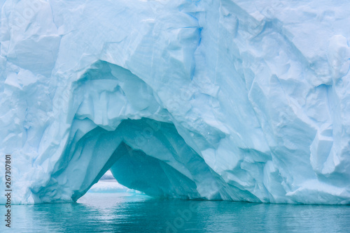 Beautiful turquoise blue iceberg floating in the Antarctic, against a foggy background