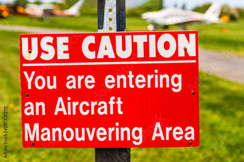 Aircraft manouvering red and white warning sign hung on post at airstrip. photo