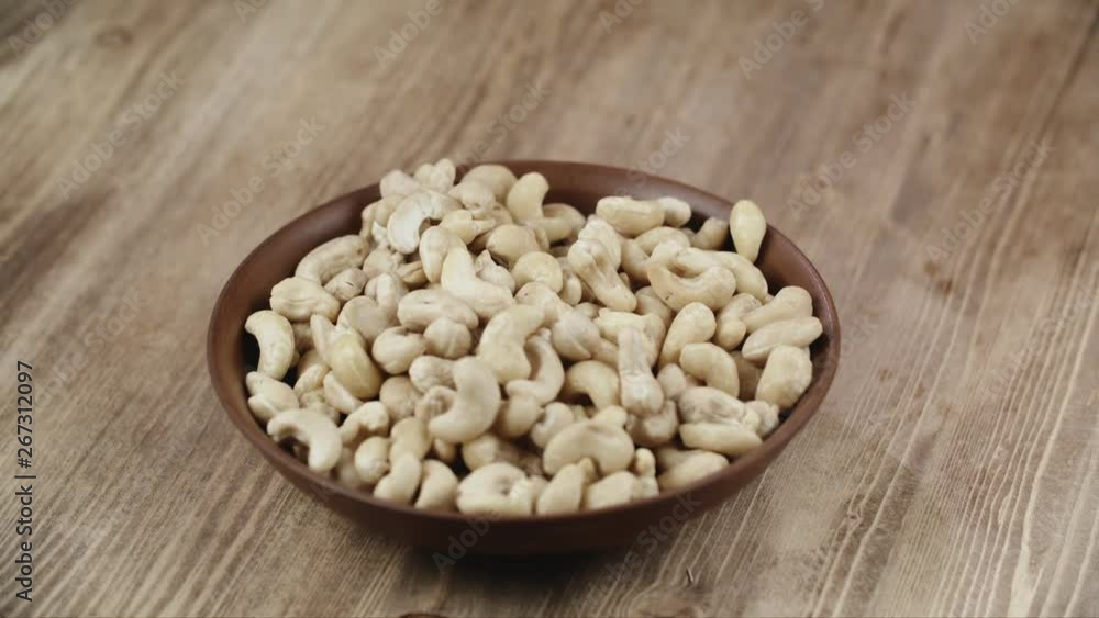 Woman Picks Up A Single Cashew, To Eat, From Her Bowl. took a nut on the right side Woman Picks Up A Single Cashew, To Eat, From Her Bowl. took a nut on the right side