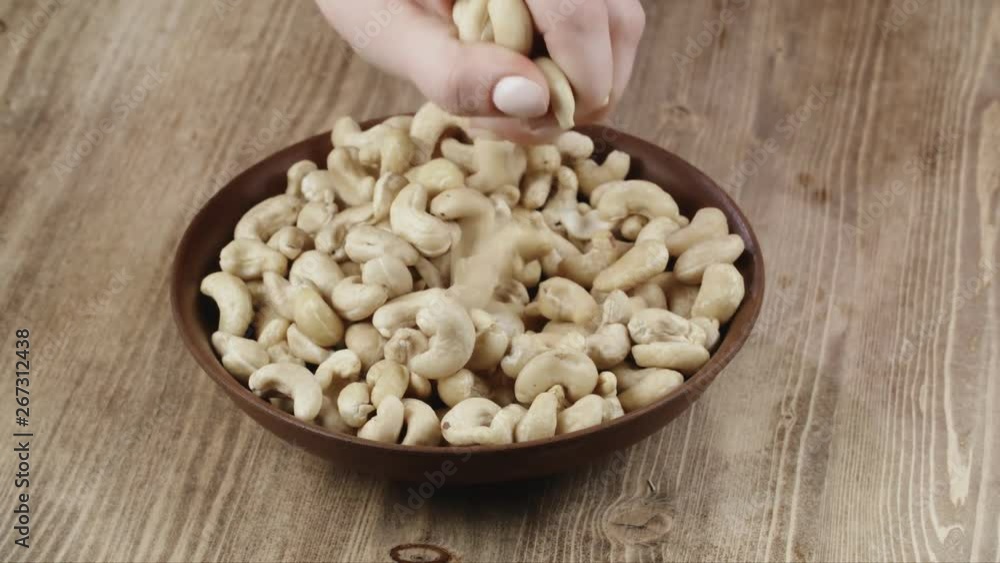 Woman Picks Up A handful Cashew, To Eat, From Her Bowl. took a nut on the left side Woman Picks Up A handful Cashew, To Eat, From Her Bowl. took a nut on the left side