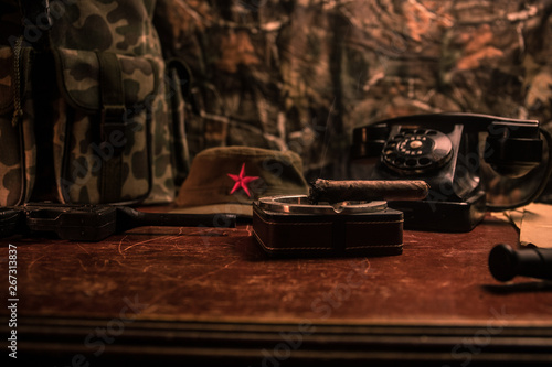 Close up of a Cuban cigar and ashtray on the wooden table. Communist dictator commander table in dark room. Army general`s work table concept. photo