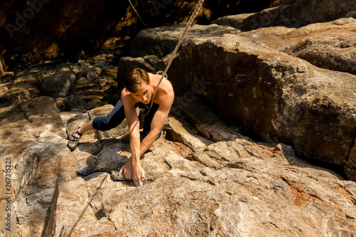 Climber Extreme climbs a rock on a rope with the top insurance, top view from above