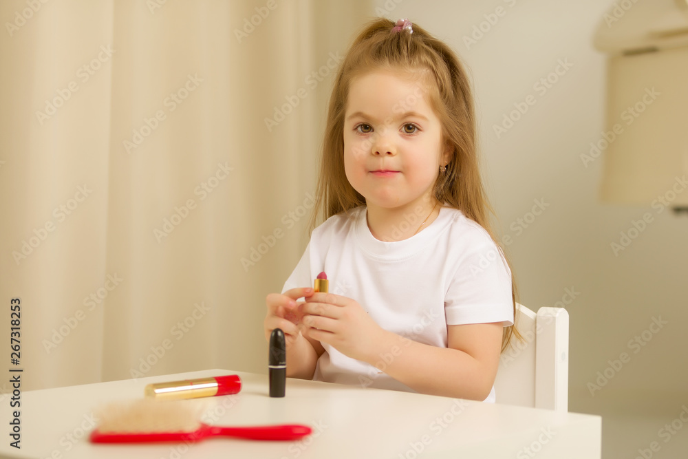 A little girl near the mirror paints lipstick lips A little girl near the mirror paints lipstick lips