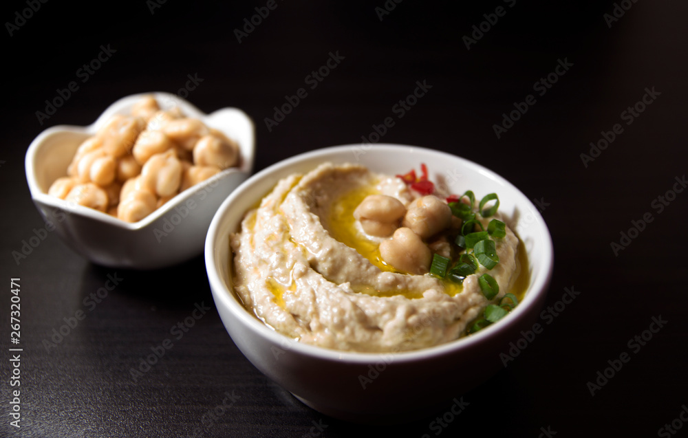 Hummus and chickpea on black background. Selective focus.
