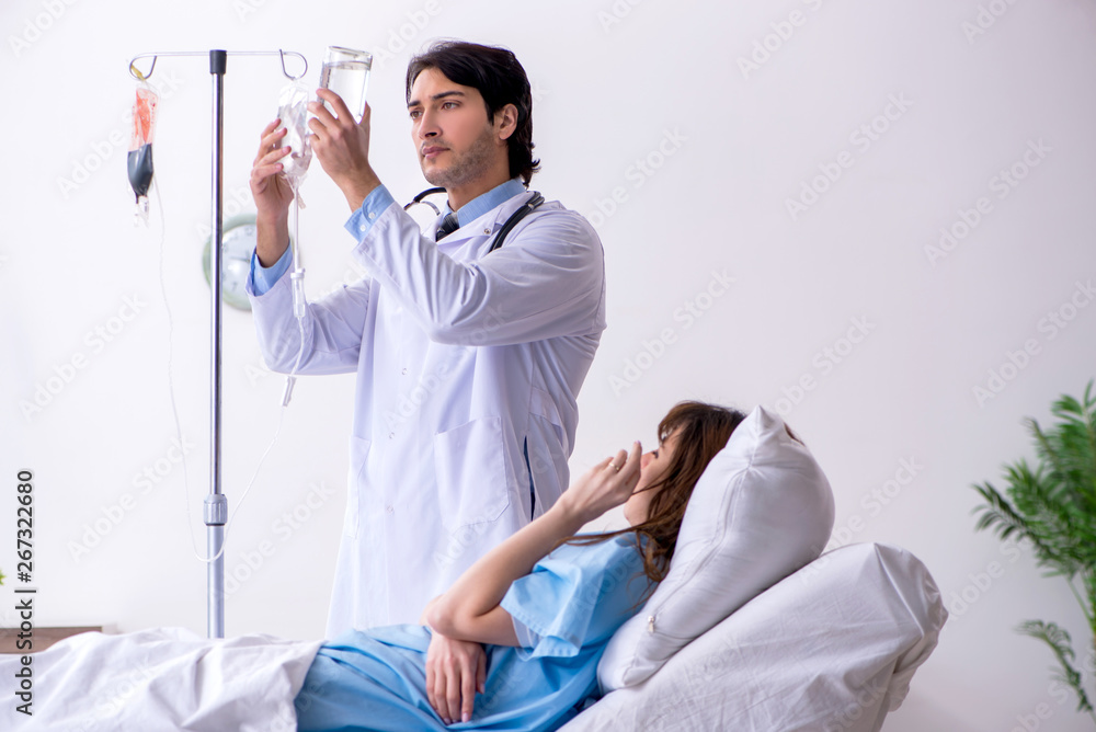 Obraz premium Male doctor visiting female patient in ward 