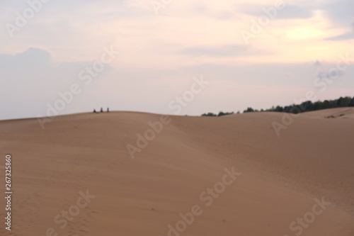 young woman relaxing at white sand dunes on sunset background