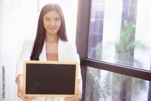 young Asian business woman holding a chalkboard.Successful business woman happy and smile.Idea note on blank blackboard.