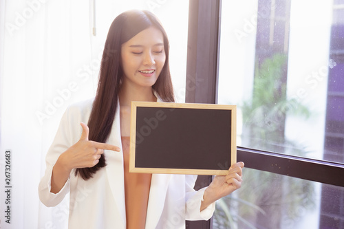 young Asian business woman holding a chalkboard.Successful business woman happy and smile.Idea note on blank blackboard.
