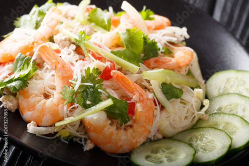 Thai noodle salad (Yum Woon Sen) served with fresh cucumbers closeup on a plate on the table. horizontal