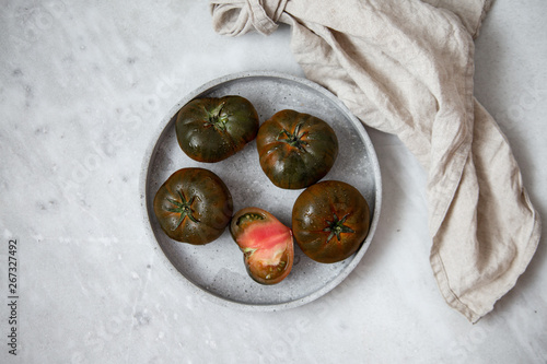 Organic Tomato Marmande black on marble backgroun with copy space. Vegan product