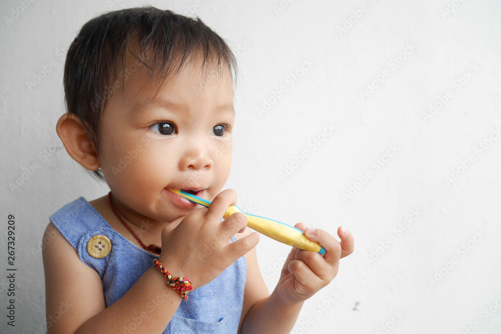 Happy Asian baby girl practice to brushing her teeth. A child aged of one year old on white background. Healthy and kid concept. Happy Asian baby girl practice to brushing her teeth. A child aged of one year old on white background. Healthy and kid concept.