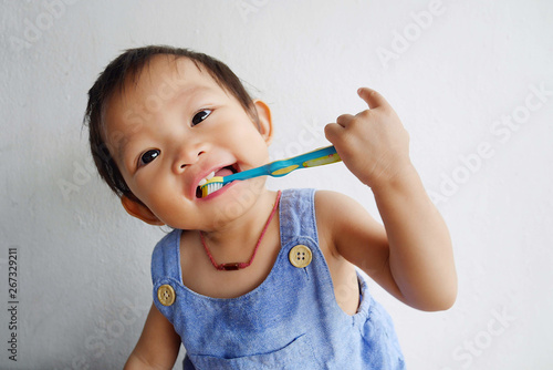 Happy Asian baby girl practice to brushing her teeth. A child aged of one year old on white background. Healthy and kid concept.
