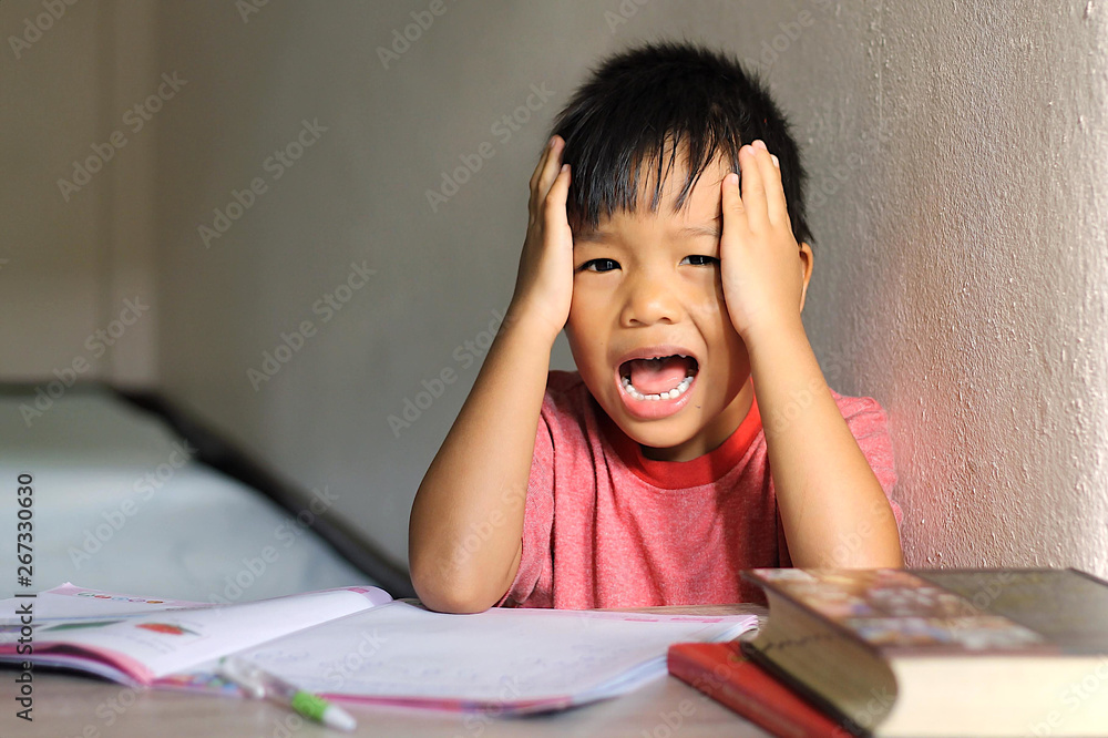 Asian student child boy have a headache and he feeling stressed because he get a lot of homework. Education and kid concept. Asian student child boy have a headache and he feeling stressed because he get a lot of homework. Education and kid concept.