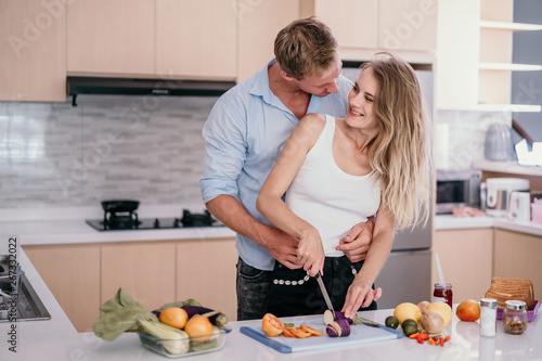 Romantic couple hugging and smiling while standing in the kitchen during cooking