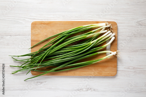 Fresh green onions on a bamboo board, overhead view. Top view, overhead, flat lay.