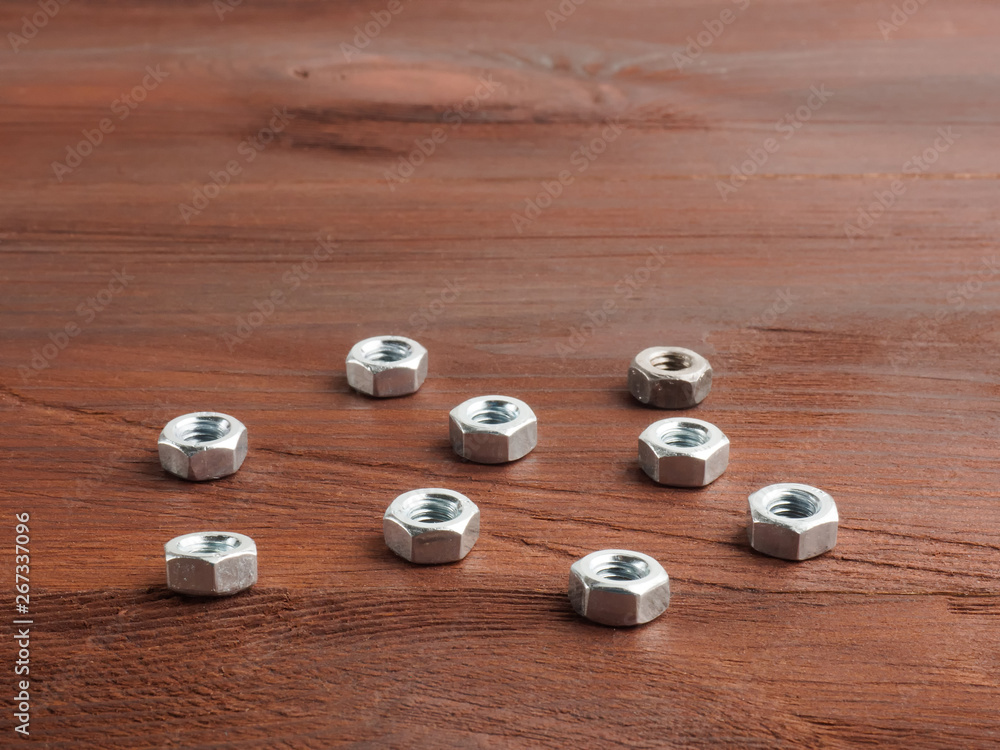 Set of silver color steel nuts on a brown wooden background Set of silver color steel nuts on a brown wooden background
