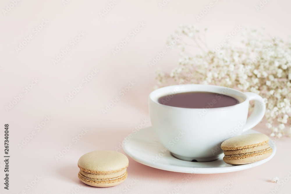 Coffee cup, macaroon and gypsophila flowers on pink background