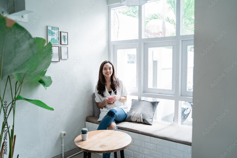 smiling asian woman with a glass of juice sitting smiling asian woman with a glass of juice sitting