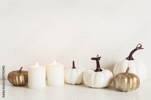 Front view composition with white pumpkins and burning candles. Autumn minimal concept