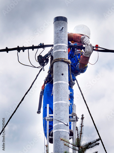 Praca montera instalacji elektrycznej na słupie energetycznym photo