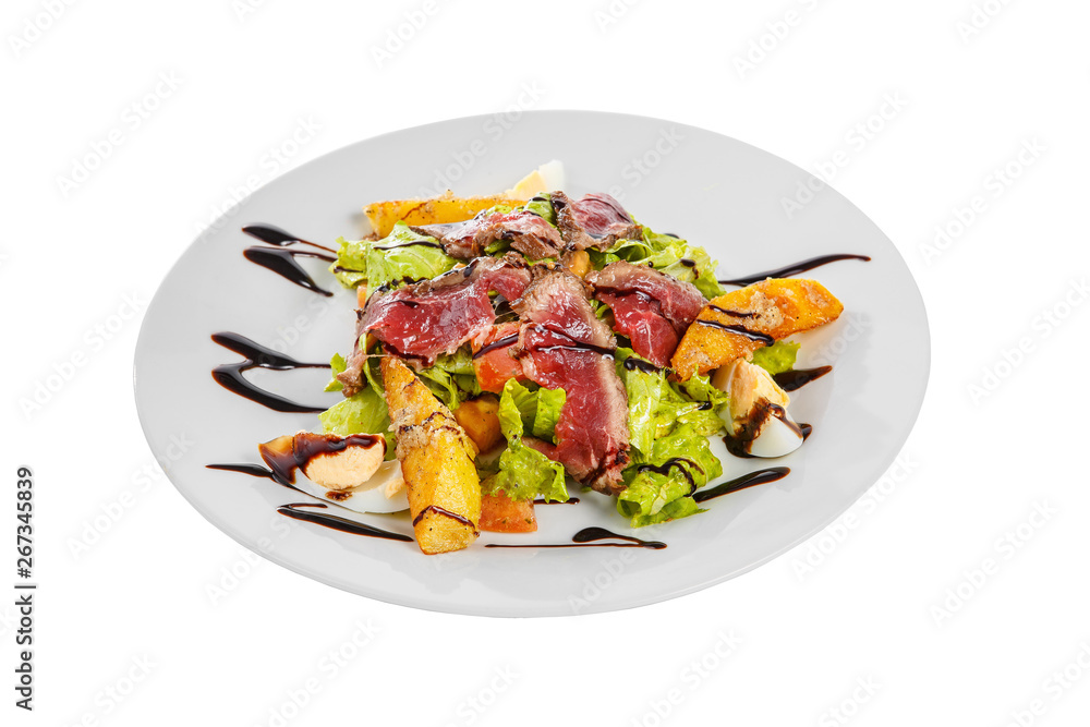 Salad with roast beef with fried potatoes, eggs, lettuce, tomatoes balsamic vinegar, sauce on plate, white isolated background, side view