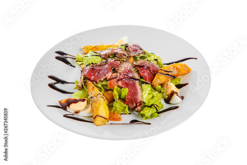 Salad with roast beef with fried potatoes, eggs, lettuce, tomatoes balsamic vinegar, sauce on plate, white isolated background, side view
