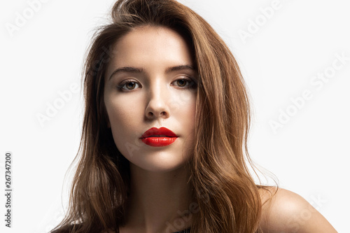Close-up fashion portrait of beautiful young woman with bright red lips. Charming girl with pretty makeup in studio. Beauty and lifestyle concept. Isolated on white background