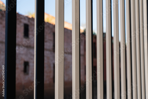 cast iron fence bars close-up with blurred brick background