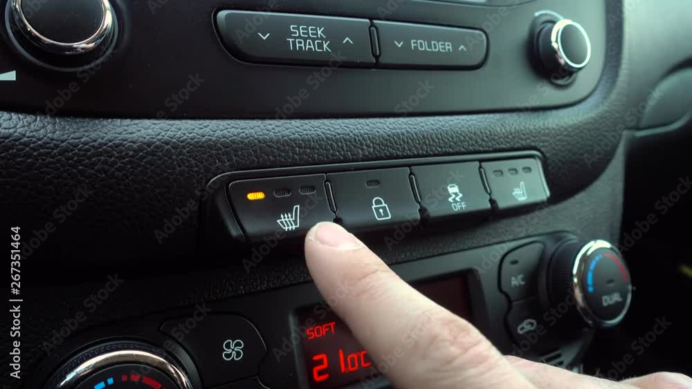 Hand presses a Heated Seat High button on a dashboard in a car Hand presses a Heated Seat High button on a dashboard in a car