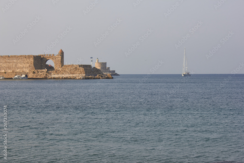 In Mandrake Harbor on the Fort of St Nicholas stands a lighthouse on a stone pier - Lighthouse of St Nicholas Fortress