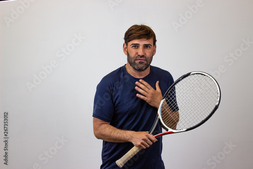 Portrait of handsome young man playing tennis holding a racket with brown hair suffering, looking at the camera. Isolated on white background. © Sergio Barceló