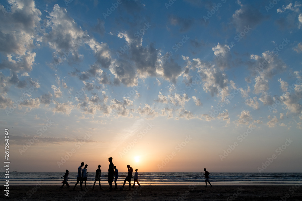 Youth playing football at Juhu beach on a summer evening.