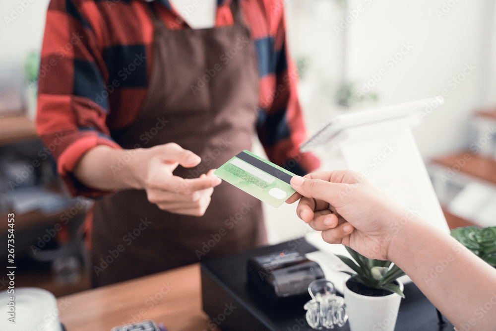 Obraz premium close up of man's hand worker in cafe counter receiving payment via credit card from customer