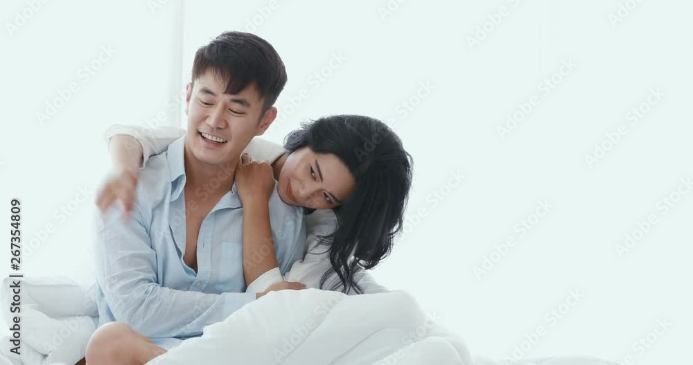 Asian couples sit on the bed, hug each other and talk tinkle in bedroom