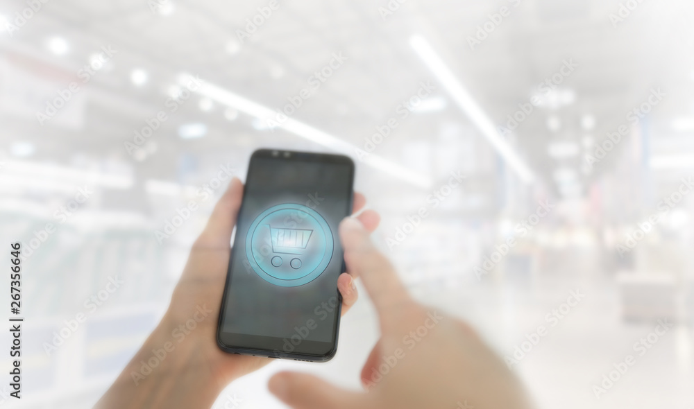 Shopping basket on a mobile phone screen. Woman Hand holding mobile phone on Supermarket blur background