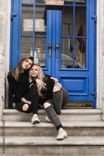 Attractive woman tourists in old european city. Beautiful young girl standing near the ancient blue door. Stylish teens traveling and enjoying summer time in Lviv, Ukraine. Girls in black 