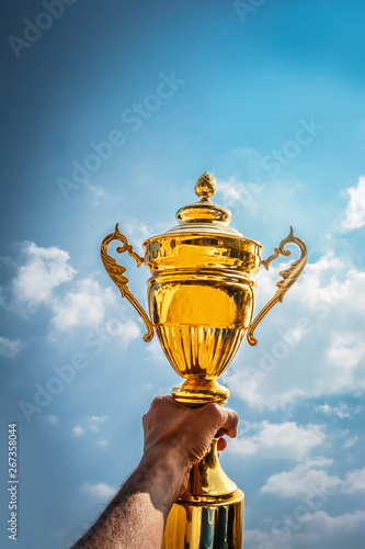 Holding up a gold trophy cup as a winner