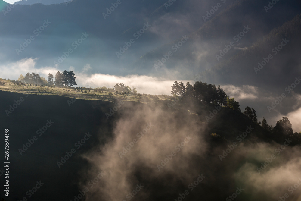 Morning mist in the mountains, sunbeams breaking through the fog, Georgia, Tusheti