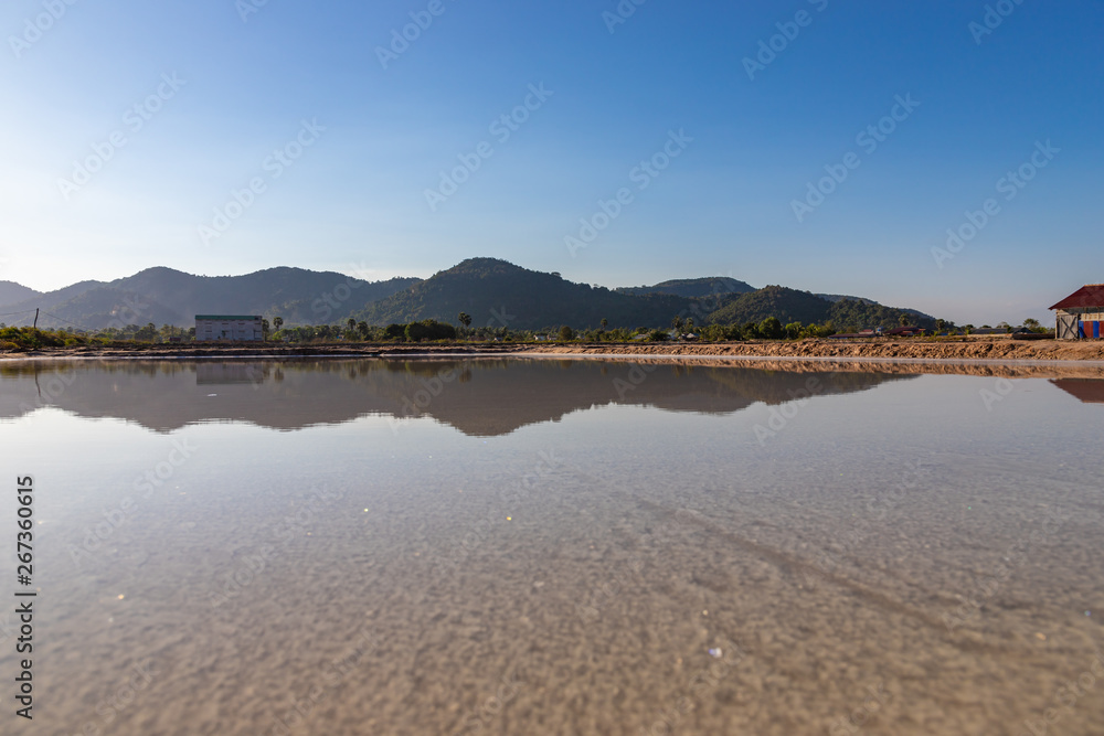 Shot of salt field with buildings in the background in Kep, Cambodia.