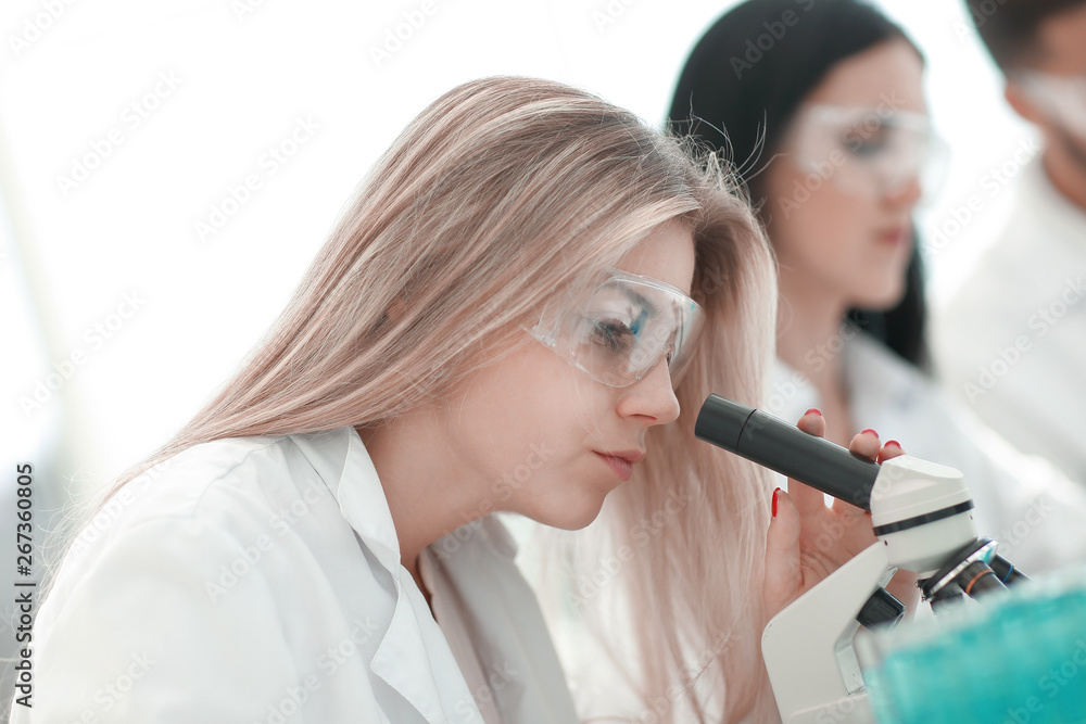 close up.serious female scientist looking into microscope in lab close up.serious female scientist looking into microscope in lab