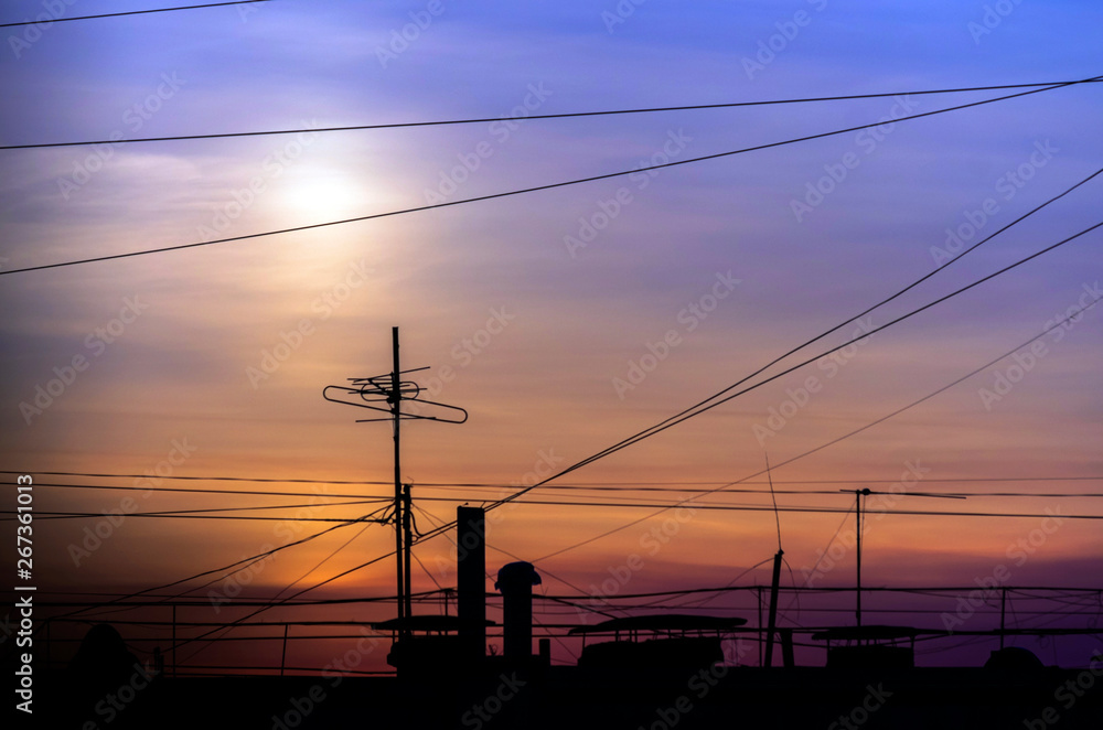 Dramatic Golden Sunset over Cityscape with Cable Wires and TV Antennas.