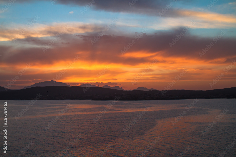 Sunrise on the Sardinian sea coast with intense orange color seen from the sea